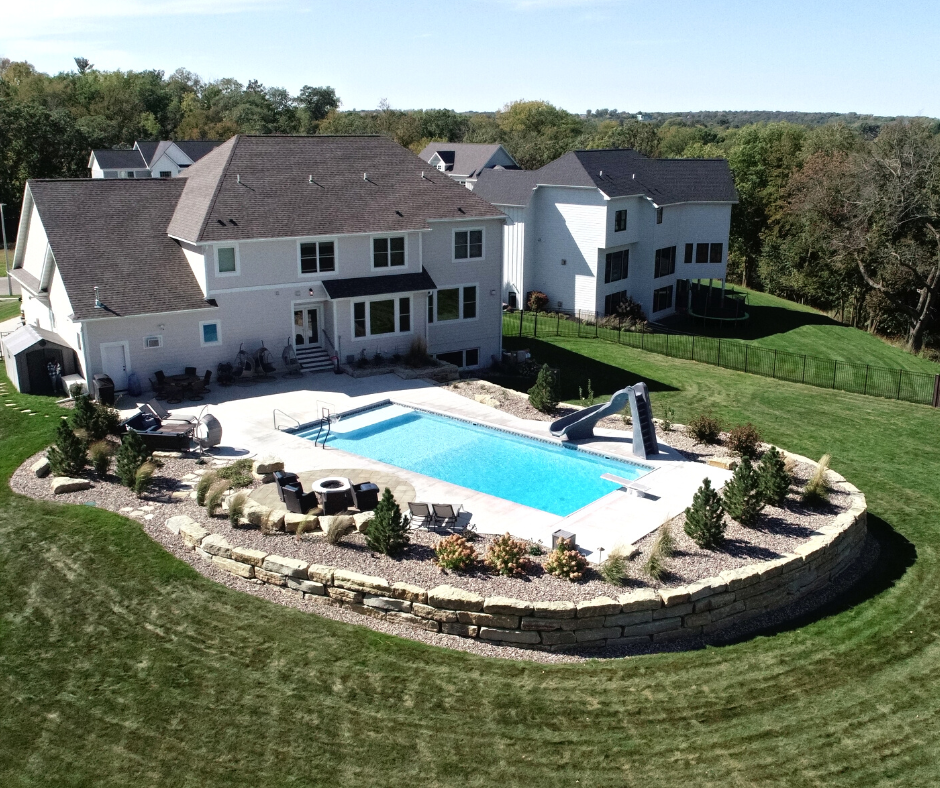 rectangular pool with slide in backyard by firepit